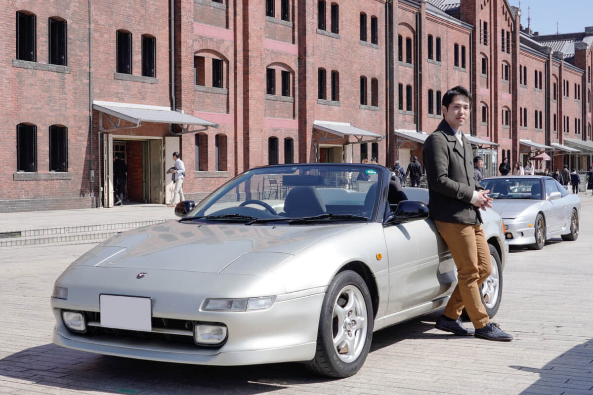 トヨタテクノクラフト MRスパイダー：横浜赤レンガ倉庫を背景に愛車と写る糸川將人さん。若き自動車エンジニアと愛車の未来は明るい