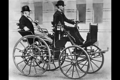 1886年のゴットリーブ・ダイムラーの4輪車。「馬なし馬車」で風防のフロントガラスやワイパー等はない。ステアリングを握るのは息子のアドルフ